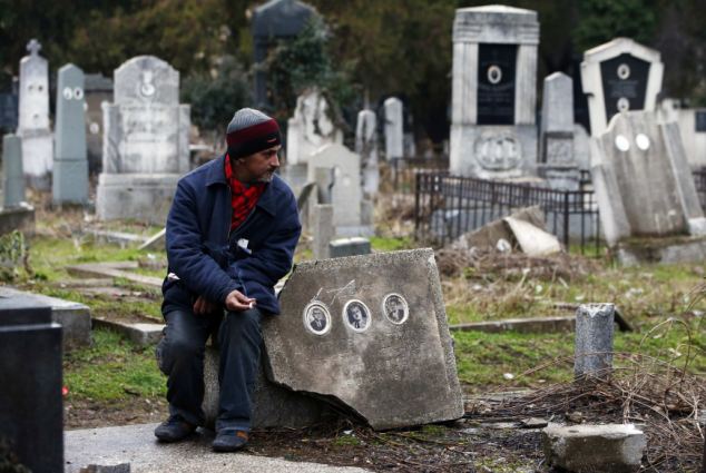 Bratislav Stojanovic, a homeless man, rests as he sits on a grave stone in the southern Serbian town of Nis